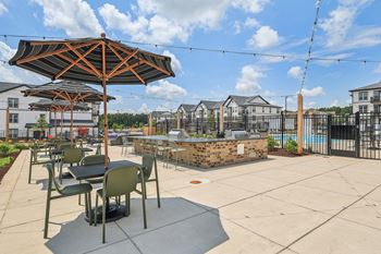 an outdoor patio with tables and umbrellas and a pool at Nook Nine, Indianapolis, 46240